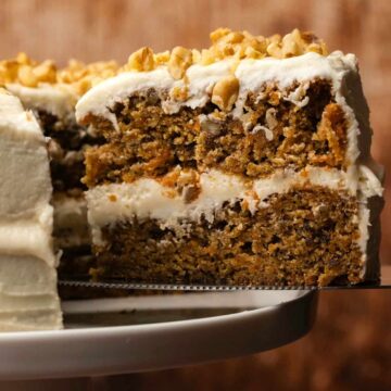 Sliced vegan carrot cake on a white cake stand.
