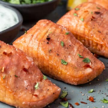 Vegan salmon on a gray plate with vegan tartar sauce and chopped cilantro.