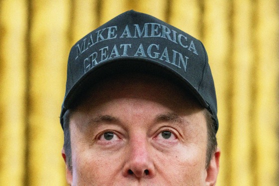 A close up photo of Elon Musk wearing a black "Make America Great Again" hat.