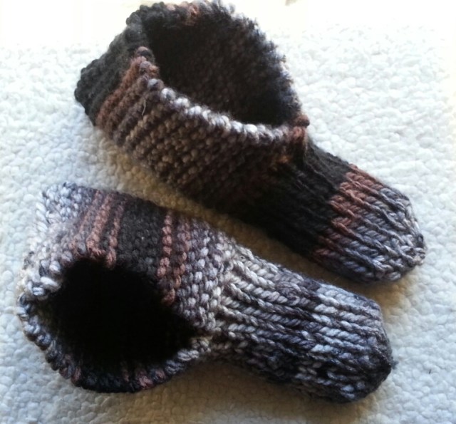 A pair of knitted slippers in brown, grey, and black