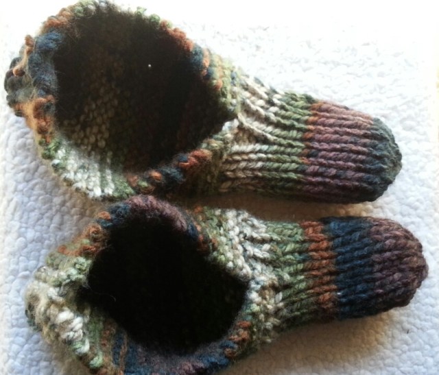 A pair of knitted slippers in green, brown, and black