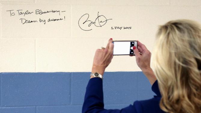 A woman photographs an autograph left by President Barack Obama on a wall at Taylor Stratton Elementary School in Nashville, Tenn., Wednesday, July 1, 2015, after Obama spoke at the school about the Affordable Care Act. (AP Photo/Mark Humphrey)