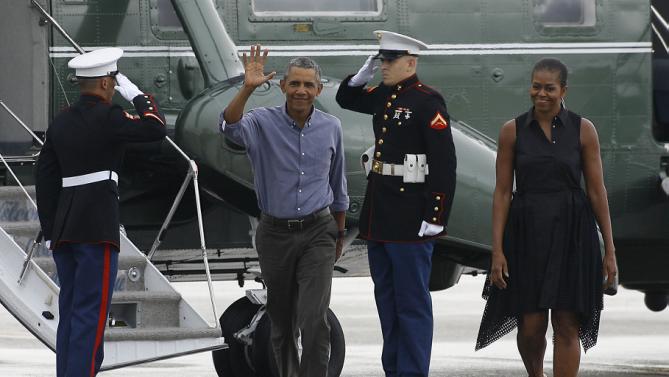 President Barack Obama and first lady Michelle Obama walk to greet supporters as they exit Marine One at the Cape Cod Coast Guard Station in Bourne, Mass., Sunday, Aug. 23, 2015, en route to Washington. (AP Photo/Stew Milne)