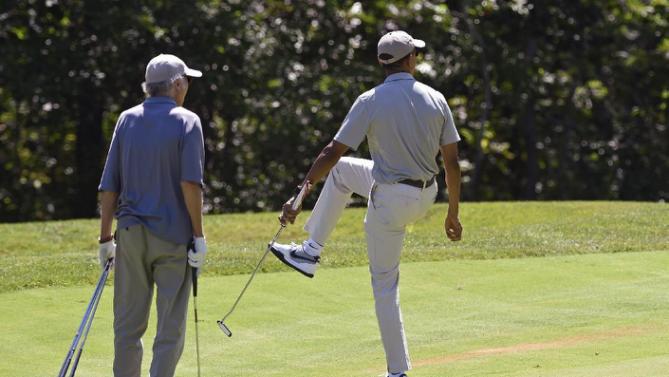 President Barack Obama, right, watches his ball as he plays golf on the first hole with Larry David, left, at Farm Neck Golf Course in Oak Bluffs, Mass., on Martha's Vineyard, Saturday, Aug. 8, 2015. The president is returning to his summer vacation spot of choice, the Massachusetts island of Martha's Vineyard, for more than two weeks of hoped-for rest coupled with extended pursuit of his favorite leisure sport: golf. (AP Photo/Susan Walsh)