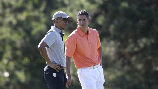President Barack Obama, left, speaks with Cyrus Walker, right, cousin of White House senior adviser Valerie Jarrett, while golfing Wednesday, Aug. 12, 2015, at Farm Neck Golf Club, in Oak Bluffs, Mass., on the island of Martha's Vineyard. The president, first lady Michelle Obama, and daughter Sasha are vacationing on the island. (AP Photo/Steven Senne)