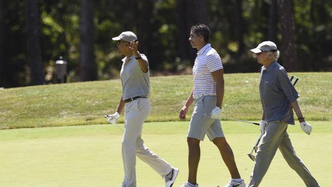 President Barack Obama, left, plays golf with Cyrus Walker, cousin of White House senior adviser Valerie Jarrett, center, and Larry David on the first hole at Farm Neck Golf Course in Oak Bluffs, Mass., on Martha's Vineyard, Saturday, Aug. 8, 2015. The president is returning to his summer vacation spot of choice, the Massachusetts island of Martha's Vineyard, for more than two weeks of hoped-for rest coupled with extended pursuit of his favorite leisure sport: golf. (AP Photo/Susan Walsh)
