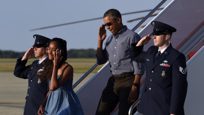 President Barack Obama salutes as he walks off of Air Force One with his daughter Malia at Andrews Air Force Base in Md., Sunday, Aug. 23, 2015. The president is returning to Washington after he and his family spent more than two weeks vacationing on the Massachusetts island of Martha's Vineyard. (AP Photo/Susan Walsh)