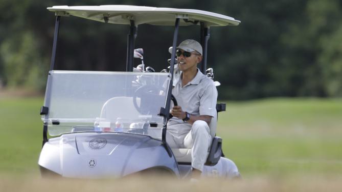 President Barack Obama drives a golf cart while golfing Saturday, Aug. 8, 2015, at Farm Neck Golf Club, in Oak Bluffs, Mass., on the island of Martha's Vineyard. Obama is spending his first full day of vacation on the island playing golf. (AP Photo/Steven Senne)