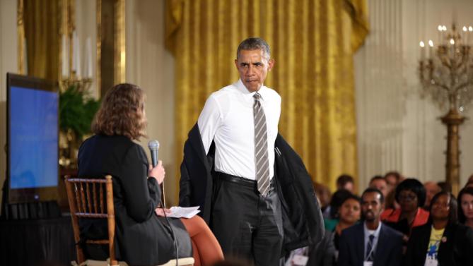 President Barack Obama takes off his jacket as he arrives to participate in a conversation co-hosted by coworker.org during the White House Summit on Worker Voice in the East Room of the White House in Washington, Wednesday, Oct. 7, 2015, with workers, employers, unions, organizers and other advocates and experts on how to energize a new generation of Americans to come together and recognize the potential power of their voice at work. On stage is Michelle Miller, co-founder of coworker.org. (AP Photo/Andrew Harnik)