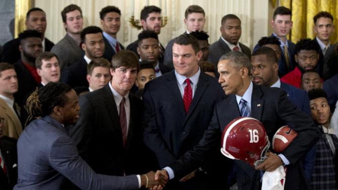 President Barack Obama shakes hands with from left, Alabama Crimson Tide running back Derrick Henry, and teammates quarterback Jake Coker, offensive lineman Ryan Kelly and linebacker Reggie Ragland, as the president is given a football, jersey and helmet during a ceremony to honor the 2015-2016 College Football Playoff National Champion Alabama Crimson Tide football team in the East Room of the White House, in Washington, Wednesday, March 2, 2016. (AP Photo/Carolyn Kaster)