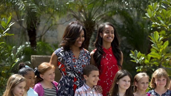U.S. First Lady Michelle Obama, center left, and her daughter Malia, center right, pose for a picture with children of U.S. embassy workers after dedicating two magnolia trees and a bench, at a small park beside Ruben Martinez Villena public library in Plaza de las Armas, Old Havana, Cuba, Tuesday, March 22, 2016. The bench bears the inscription in English and Spanish "A gift to the people of Cuba from Mrs. Michelle Obama, first lady of the U.S., March 2016." (AP Photo/Rebecca Blackwell)