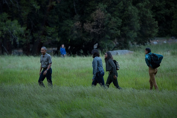 US President Barack Obama, first lady Michelle Obama an dtheir daughters Sasha Obama and Malia walk through Ahwahnee Meadow after arriving on Marine One June 17, 2016 in Yosemite Vally, California. / AFP / Brendan Smialowski (Photo credit should read BRENDAN SMIALOWSKI/AFP/Getty Images)