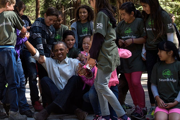 Children help US President Barack Obama stand after he spoke to them about the "Every Kid in the Park" initiative while celebrating the 100th year of US National Parks, on June 18, 2016 in Yosemite Valley, California. / AFP / Brendan Smialowski (Photo credit should read BRENDAN SMIALOWSKI/AFP/Getty Images)