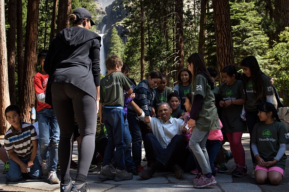 Children help US President Barack Obama stand after he spoke to them about the "Every Kid in the Park" initiative while celebrating the 100th year of US National Parks, on June 18, 2016 in Yosemite Valley, California. / AFP / Brendan Smialowski (Photo credit should read BRENDAN SMIALOWSKI/AFP/Getty Images)
