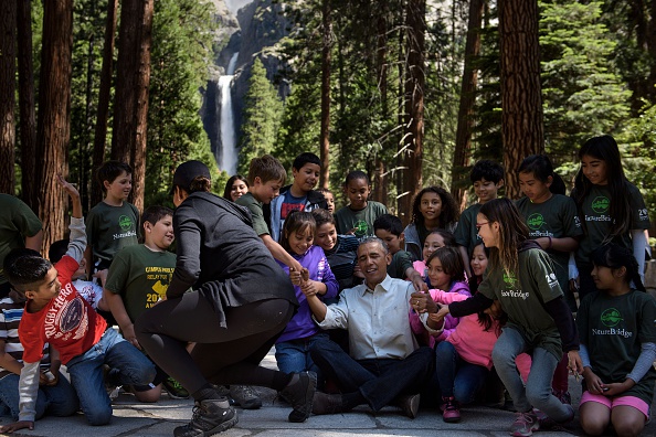 US First Lady Michelle Obama watches as children help US President Barack Obama stand after he spoke to them about the "Every Kid in the Park" initiative in Yosemite National Park, California, while celebrating the 100th year of US National Parks June 18, 2016. / AFP / Brendan Smialowski (Photo credit should read BRENDAN SMIALOWSKI/AFP/Getty Images)