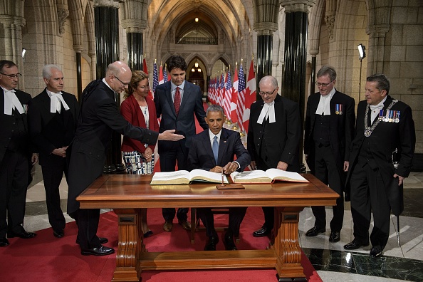 Canadian Prime Minister Justin Trudeau and others watch as US President Barack Obama signs a guest book at Parliament Hill during the North American Leaders Summit on June 29, 2016 in Ottawa, Ontario. / AFP / Brendan Smialowski (Photo credit should read BRENDAN SMIALOWSKI/AFP/Getty Images)