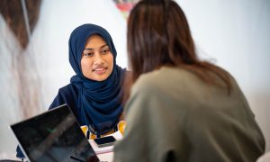 Two students speaking over a laptop.