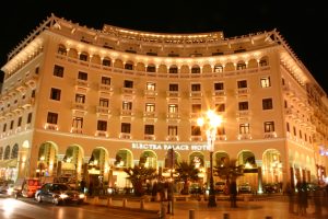 A beautifully illuminated hotel building at night, featuring a grand façade with multiple arched windows and balconies.