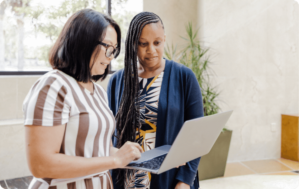 Two teachers are looking at a laptop.