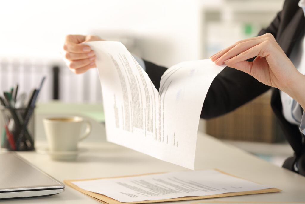 Close up of business woman hands tearing contract document sitting on a desk at the office