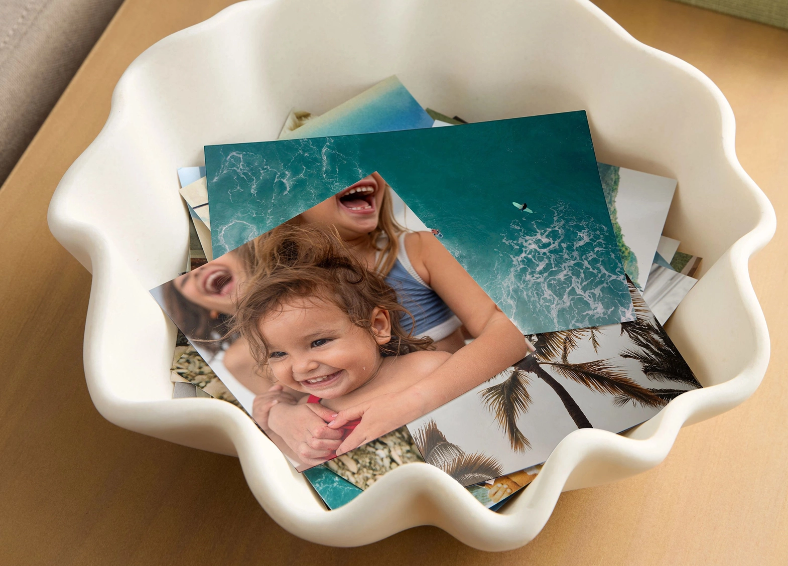 Printed photos showing children and ocean imagery placed in a shallow white bowl.