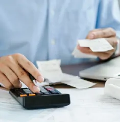 a close up of a persons hand pressing buttons on a calculator whilst holding a receipt