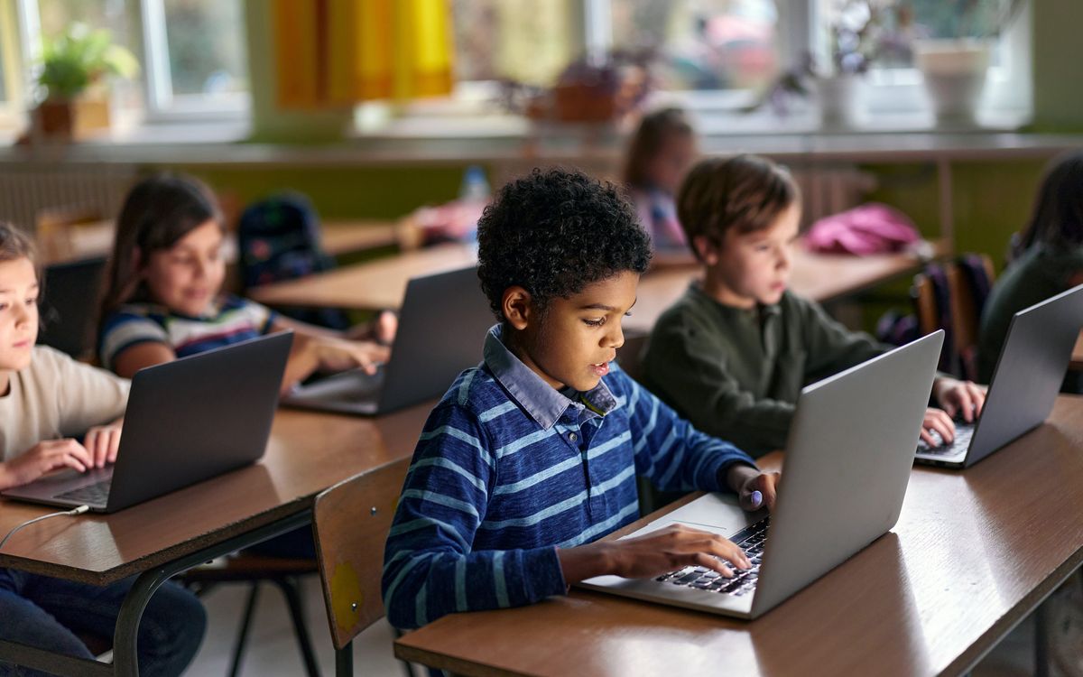Elementary school students working on laptop computers at their desks.