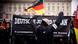 Young, white men dressed in black wave German flags and raise their fists at a rally by the right-wing extremist group 'Deutsche Jugend Voran' in Berlin Young, white men dressed in black wave German flags and raise their fists at a rally by the right-wing extremist group 'Deutsche Jugend Voran' in Berlin