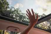 person touching clear glass vehicle sun roof