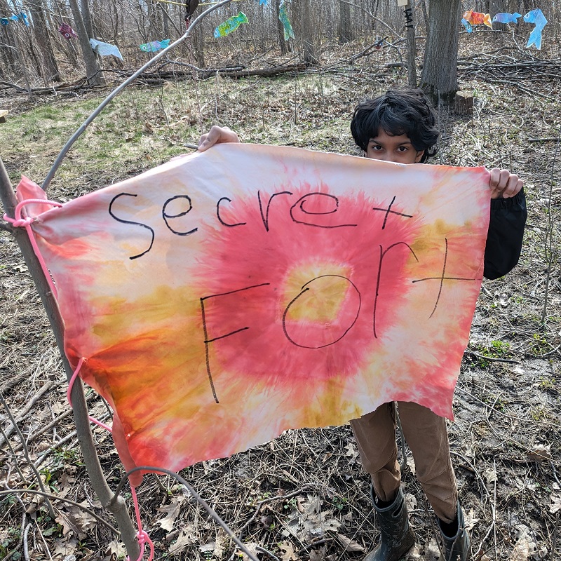 Nature School student at Kortright displays a tie-dyed banner that says SECRET FORT