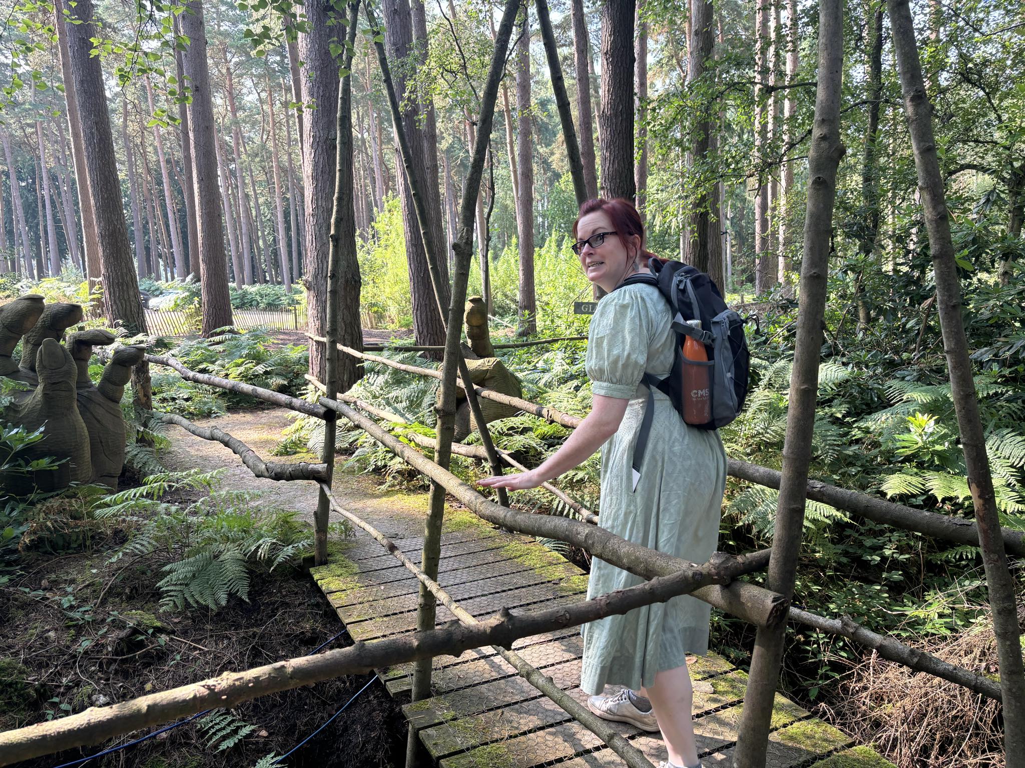 Vicky at the Dreamery Gardens near York, standing on a foot bridge among trees.