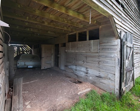 joe_9237-comp5-flat-use1 This is the corn crib and storage side of the barn. It is floored to keep feed, leather tack and other supplies off the ground and as far away from hungry varmints as possible. The hole in the ground on this side attests to that this side still as some attraction to burrowing critters. Herman has, among other things, a hammer mill stored on this side.