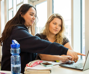 A photo of two students researching something on their laptop