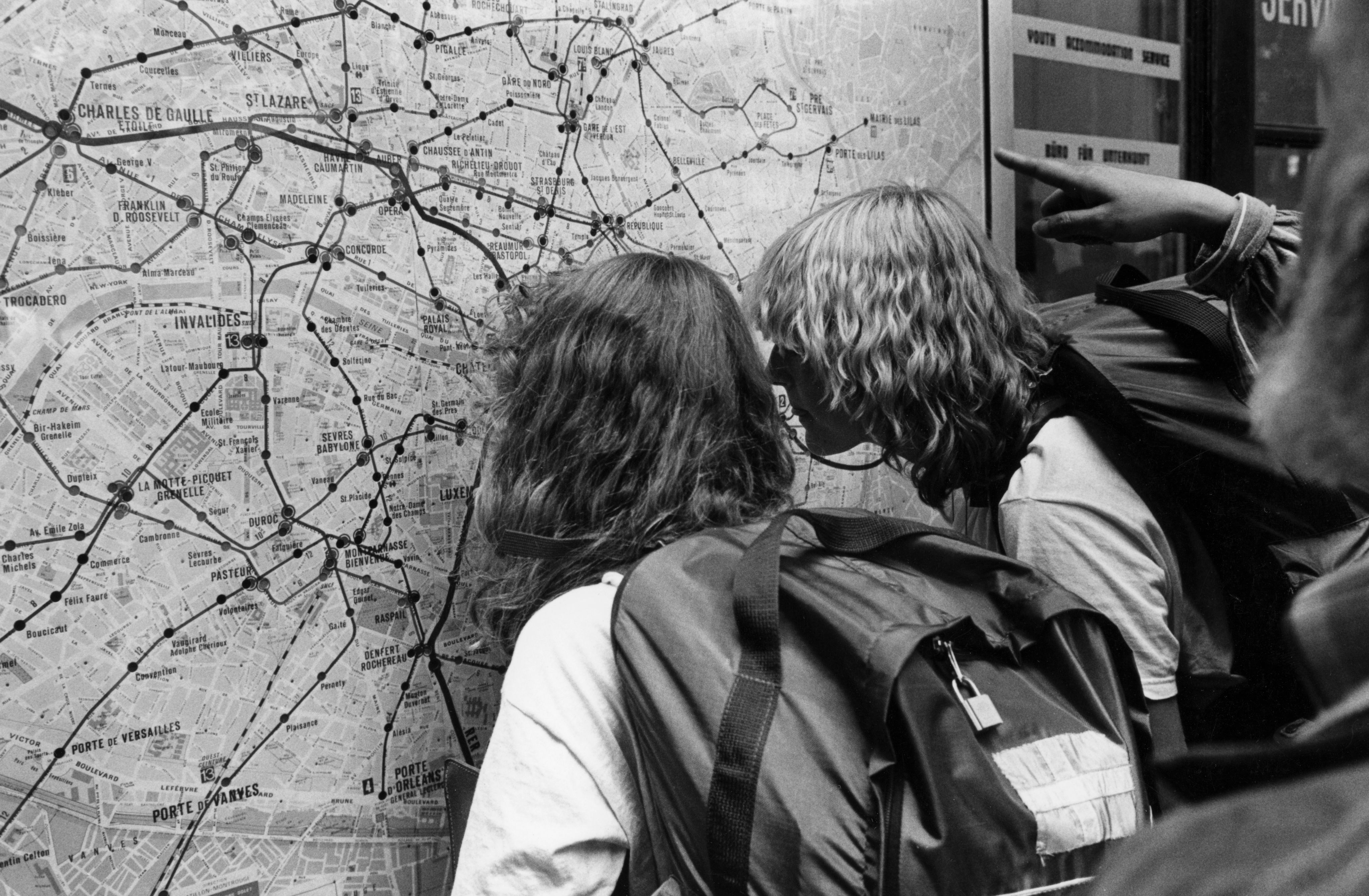 Des touristes observent attentivement le plan du métro parisien (autour de 1980).