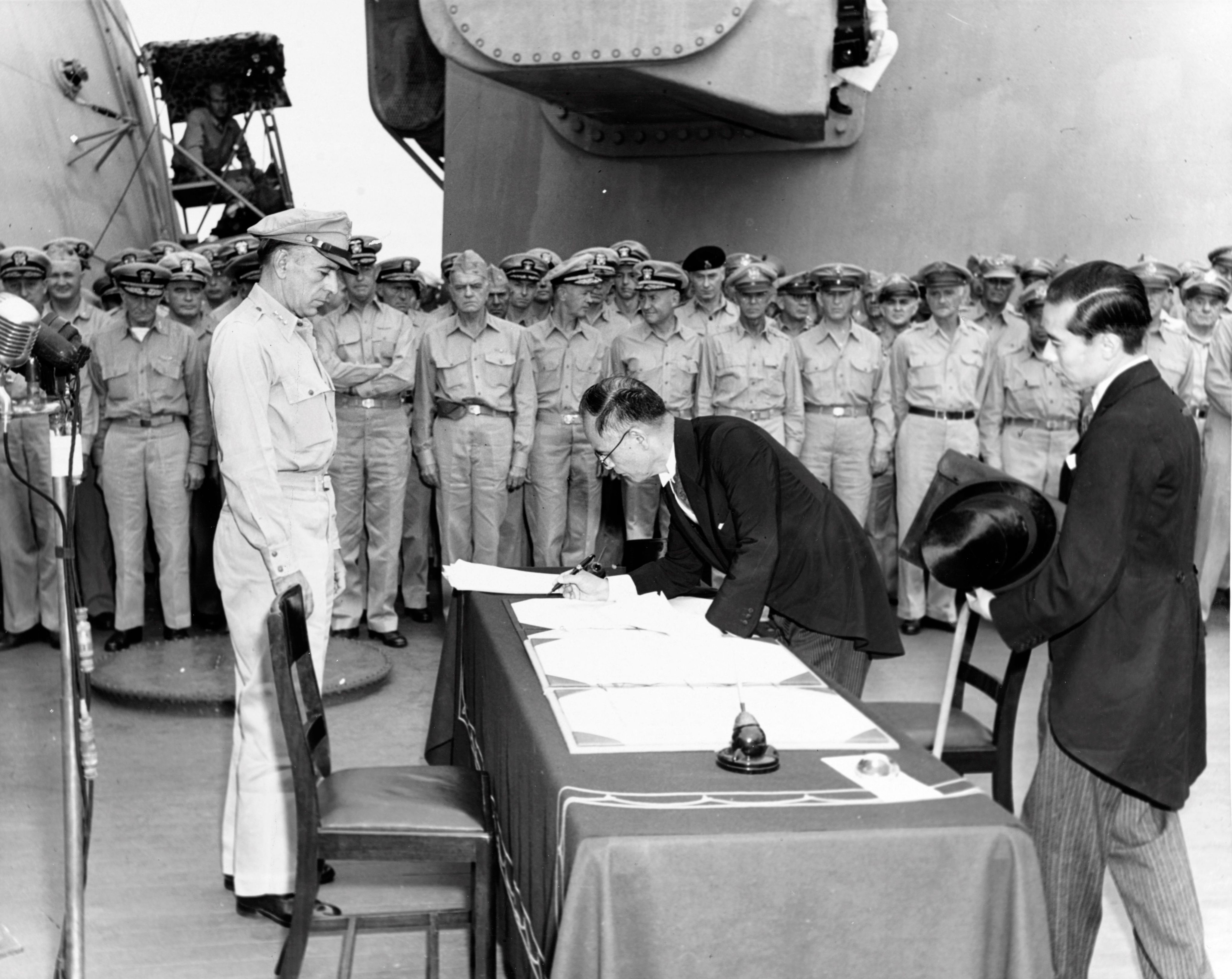 Le ministre des Affaires étrangères du Japon, Mamoru Shigemitsu, signe les actes de capitulation du Japon à bord de l'USS Missouri sous le regard du général Sutherland, le 2 septembre 1945.