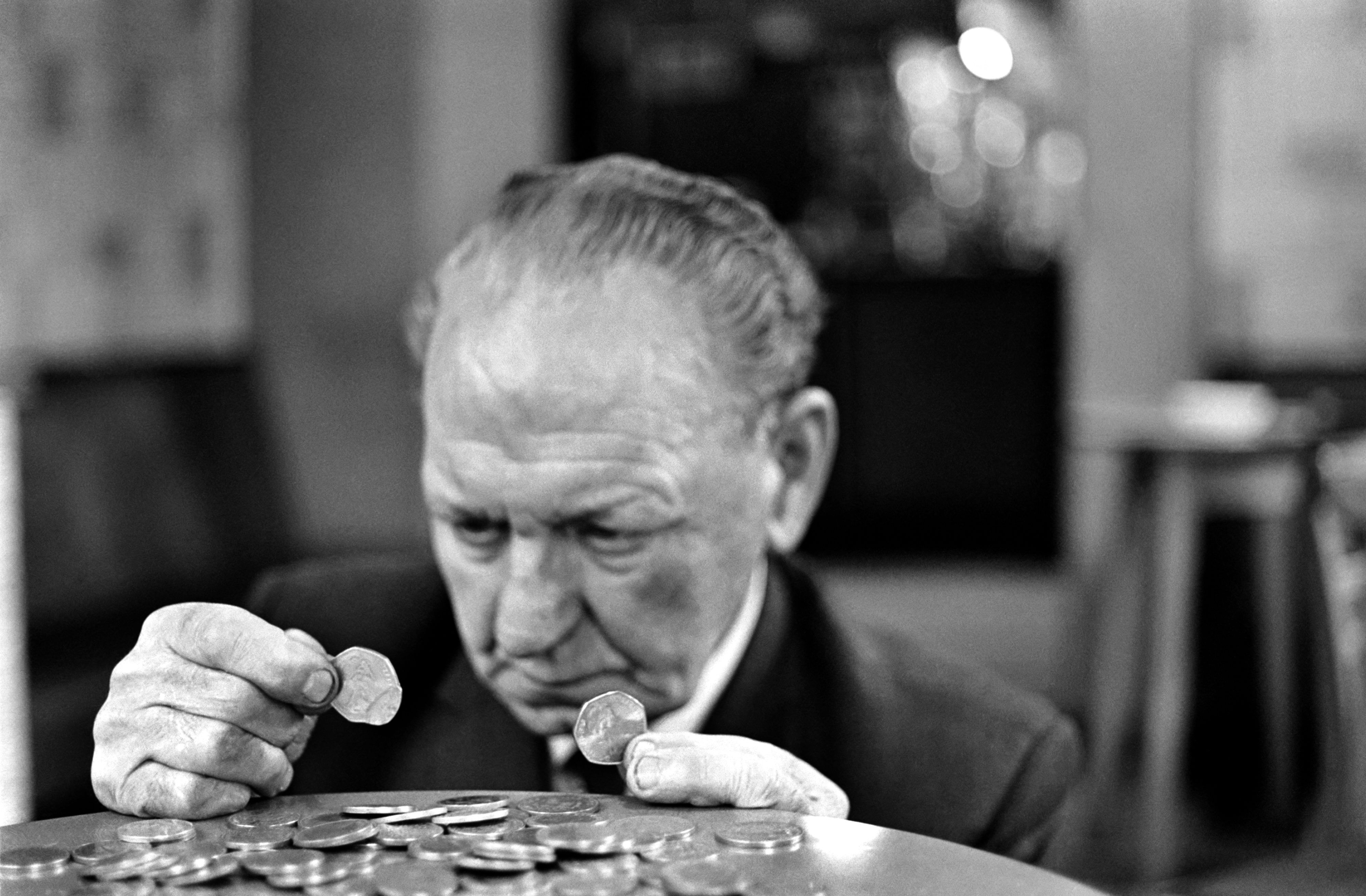Un vieil homme regarde de près une pièce de monnaie, novembre 1969