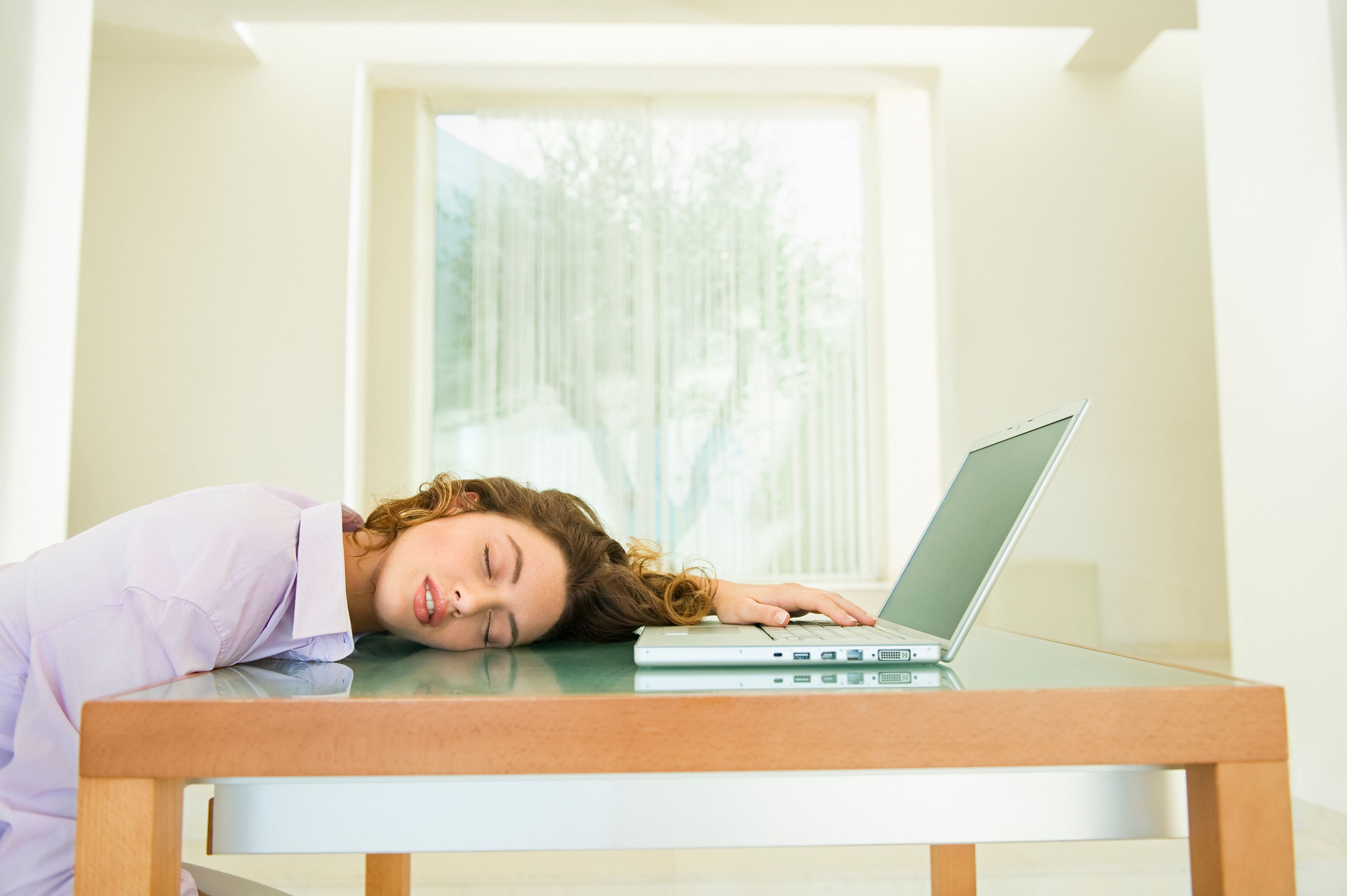Jeune femme endormie sur son ordinateur portable
