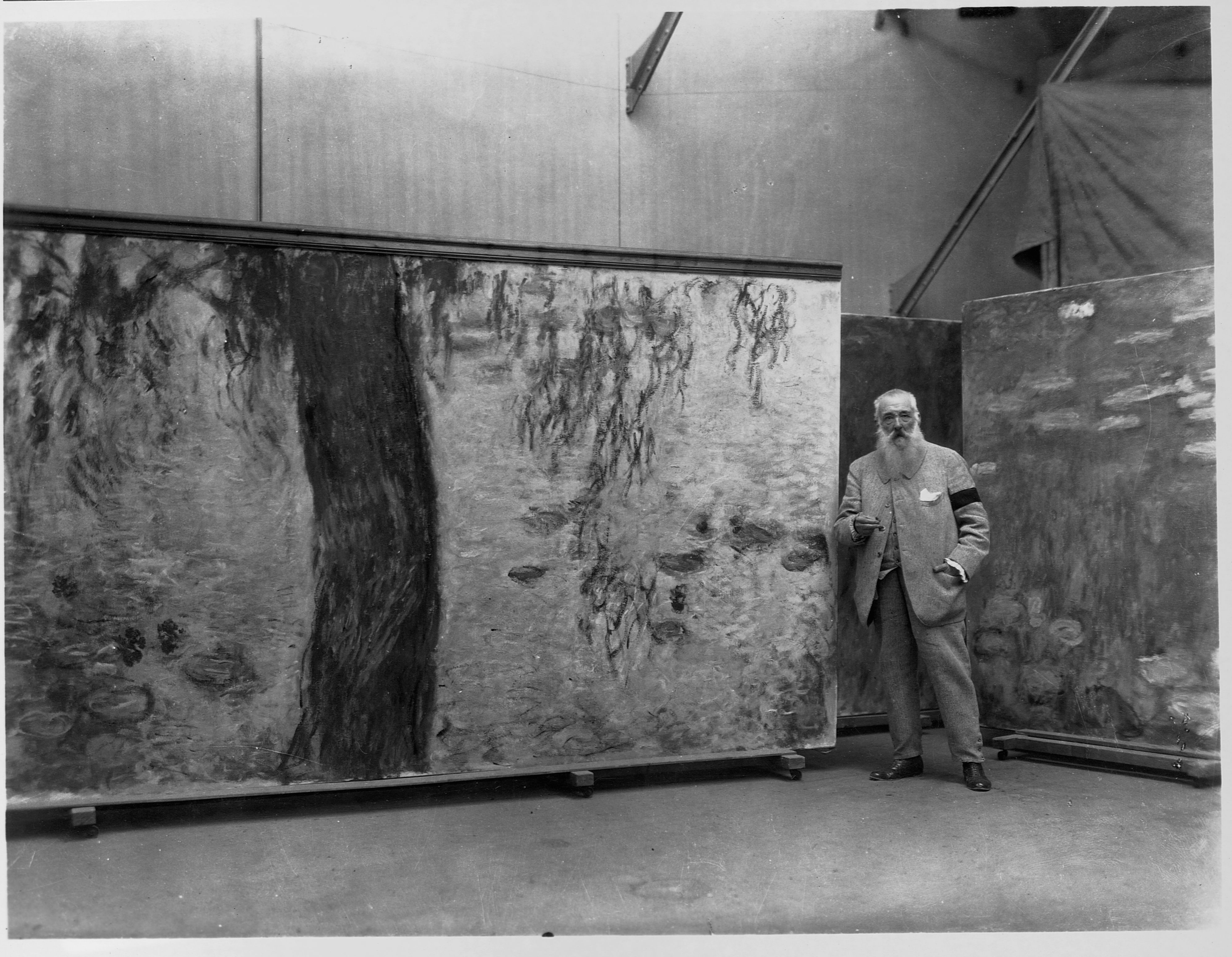 Claude Monet debout dans son atelier avec un panneau de sa fresque murale Les Nymphéas. Musée de l'Orangerie.