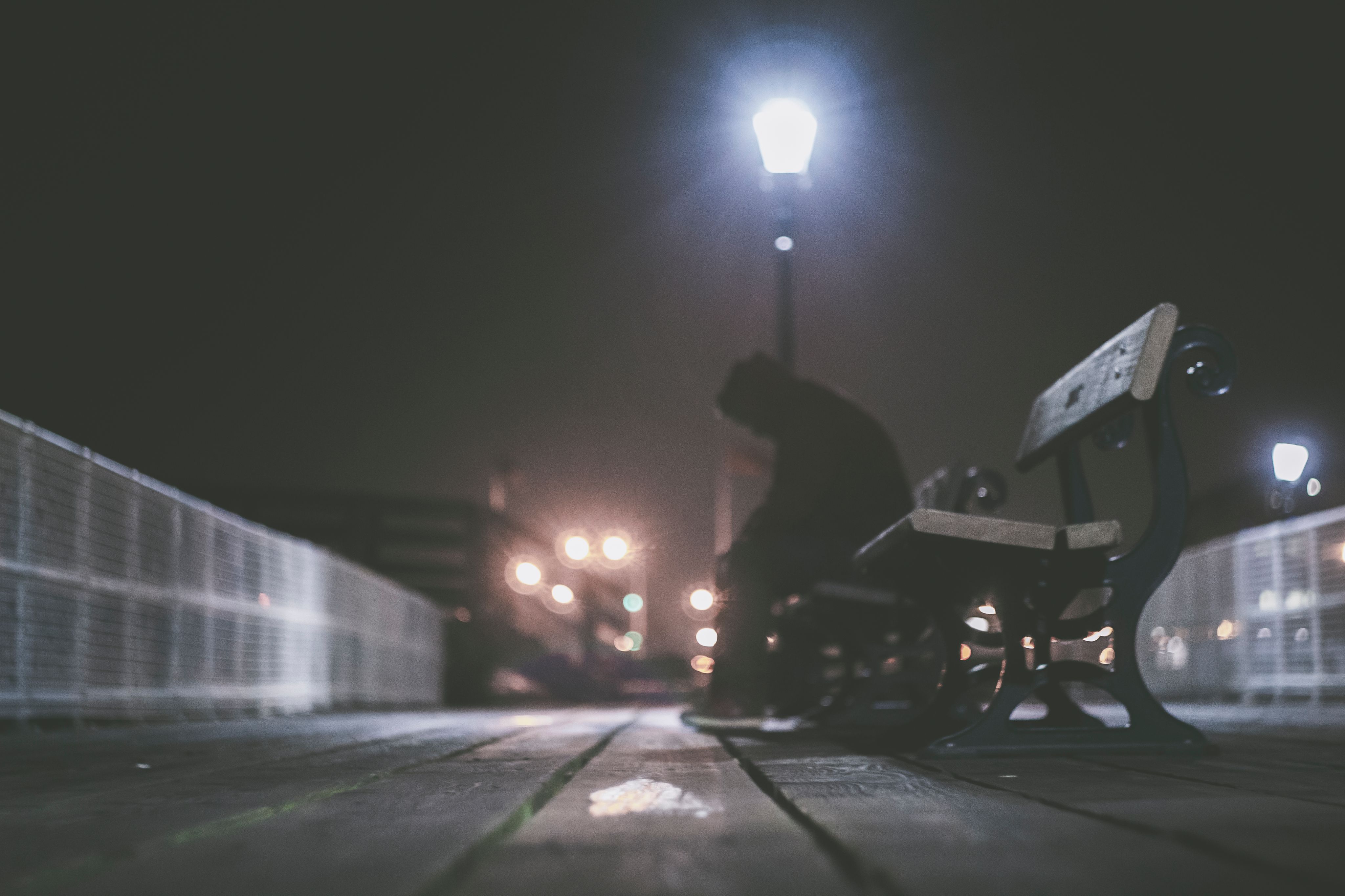 Un homme seul sur un banc, la nuit.