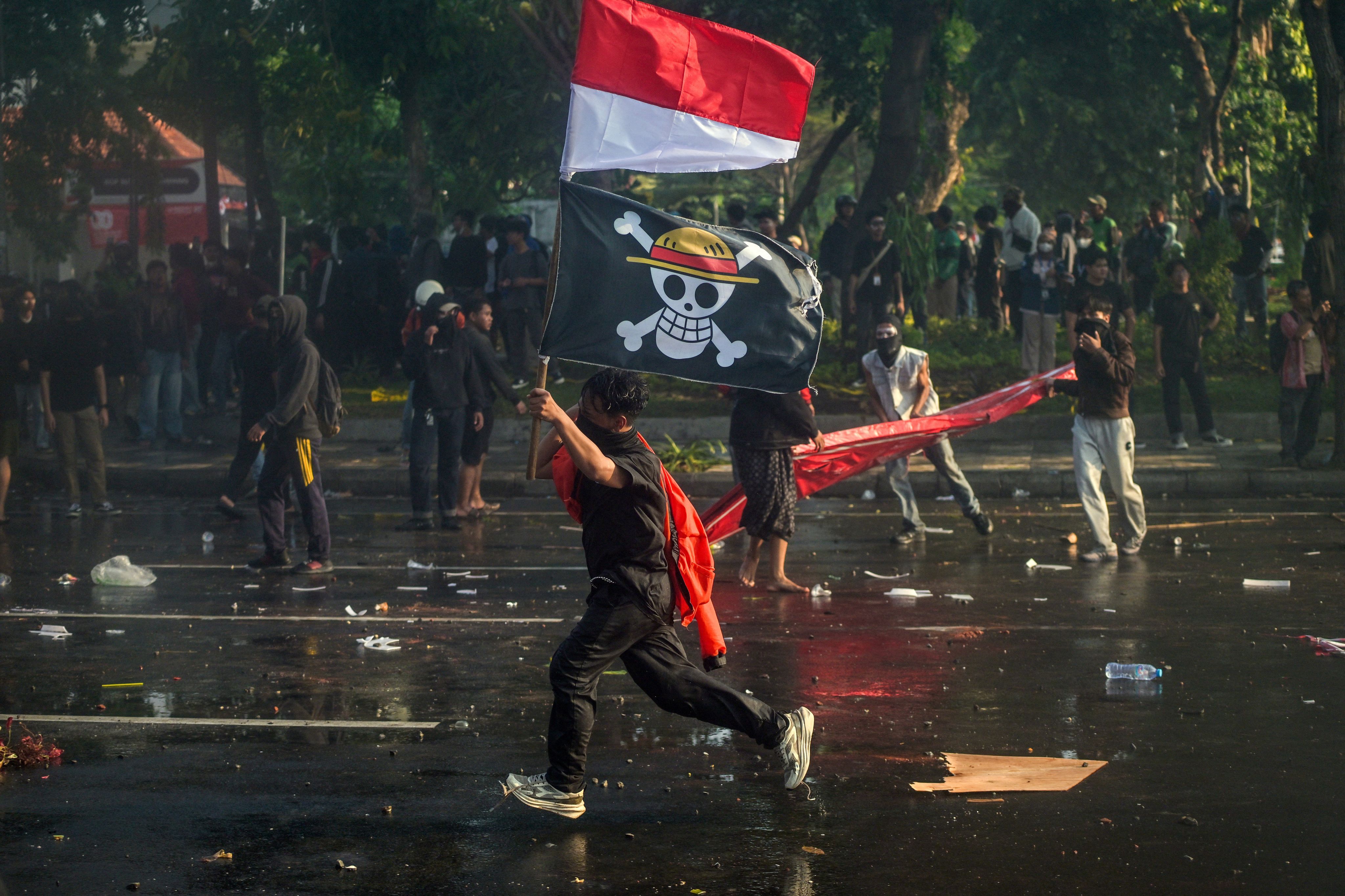 Un manifestant avec le drapeau national indonésien et un drapeau pirate du manga japonais 'One Piece', le 29 août 2025 à Surabaya