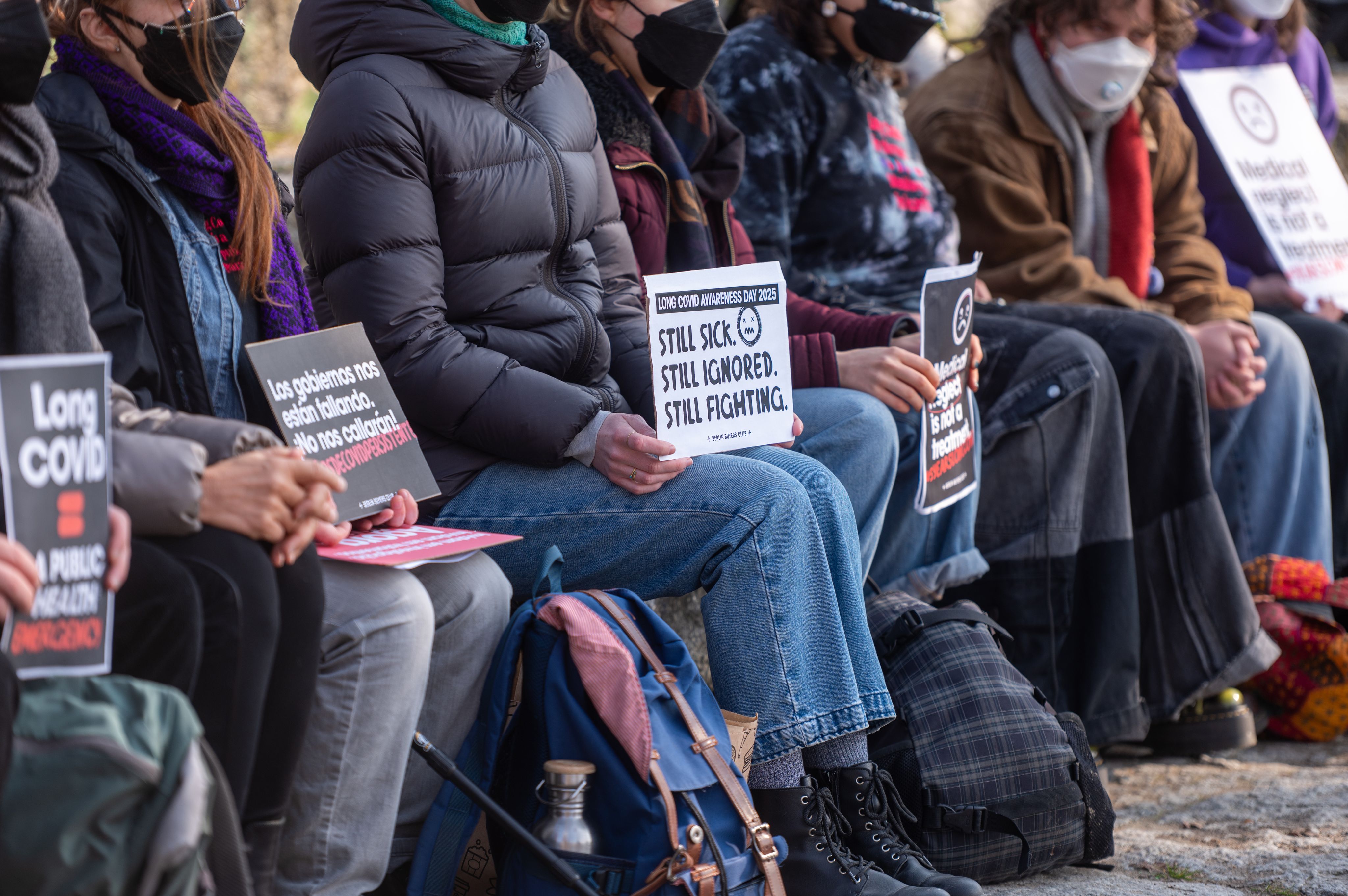 15/03/2025, Berlin : Des participants brandissent des pancartes lors d’un rassemblement au Mauerpark à l’occasion de la Journée internationale de sensibilisation au Covid long