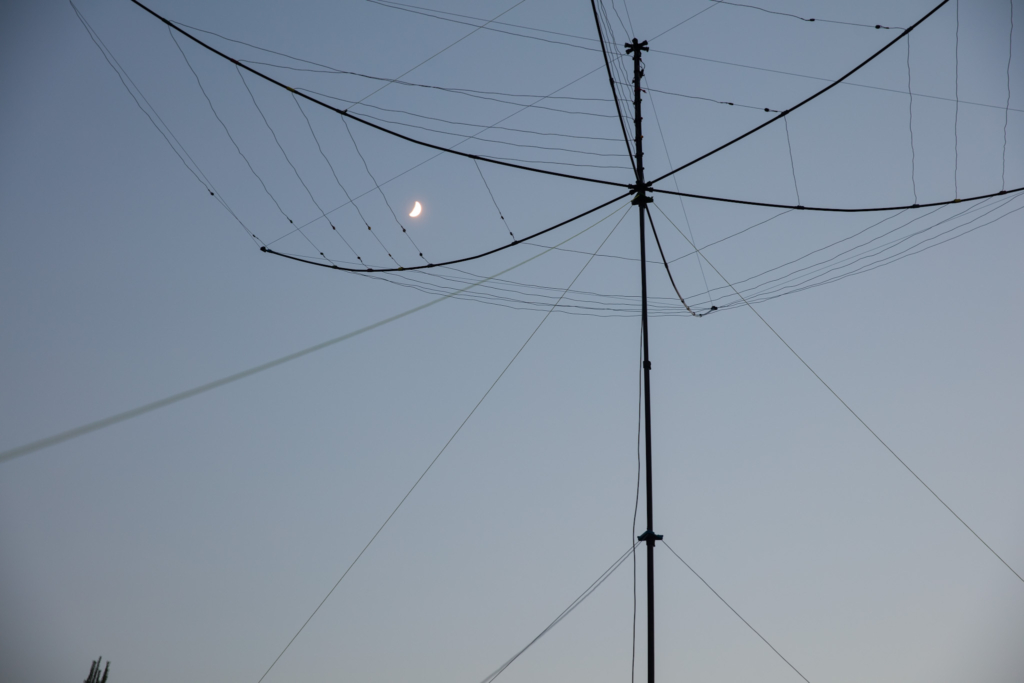 Hex beam amateur radio antenna silhouetted against a twilight sky with a crescent moon