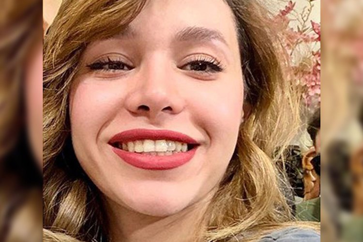 Young woman with brown hair and red lipstick smiles.