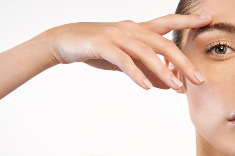 A woman's hands touching her perfect skin, with a close-up of her right eye and lips.