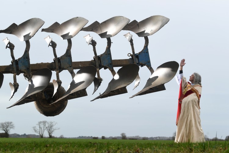 Reverend Jo King blessing the plough of farmer Jonathan Bentall in a field.