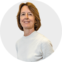 a woman wearing a white sweater and gold earrings smiles for the camera