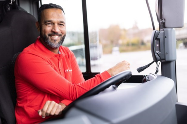 Conducteur de bus au volant avec un polo rouge Transdev