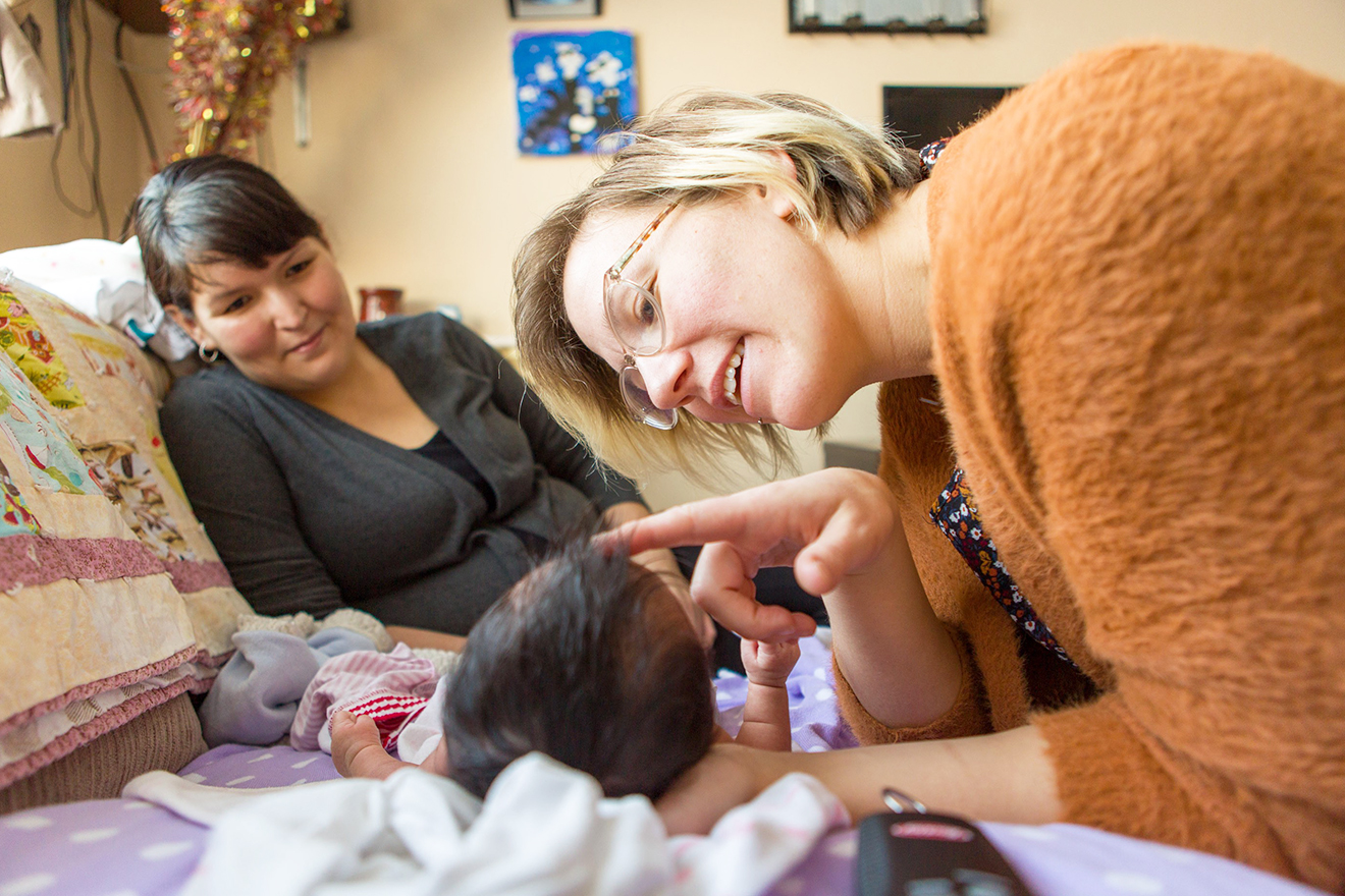 Heather Heinrichs is a midwife working in remote Hay River in Canada’s Northwest Territories. A midwife strokes the forehead of a baby whilst the mother affectionately looks at the child.