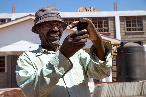 حولت تقنيات الدفع عبر الهات الهواتف المحمولة إلى أدوات مالية لما يزيد عن بليون فرد. رجل يحاول قراءة شاشة تلفونه المحمول تحت أشعة الشمش