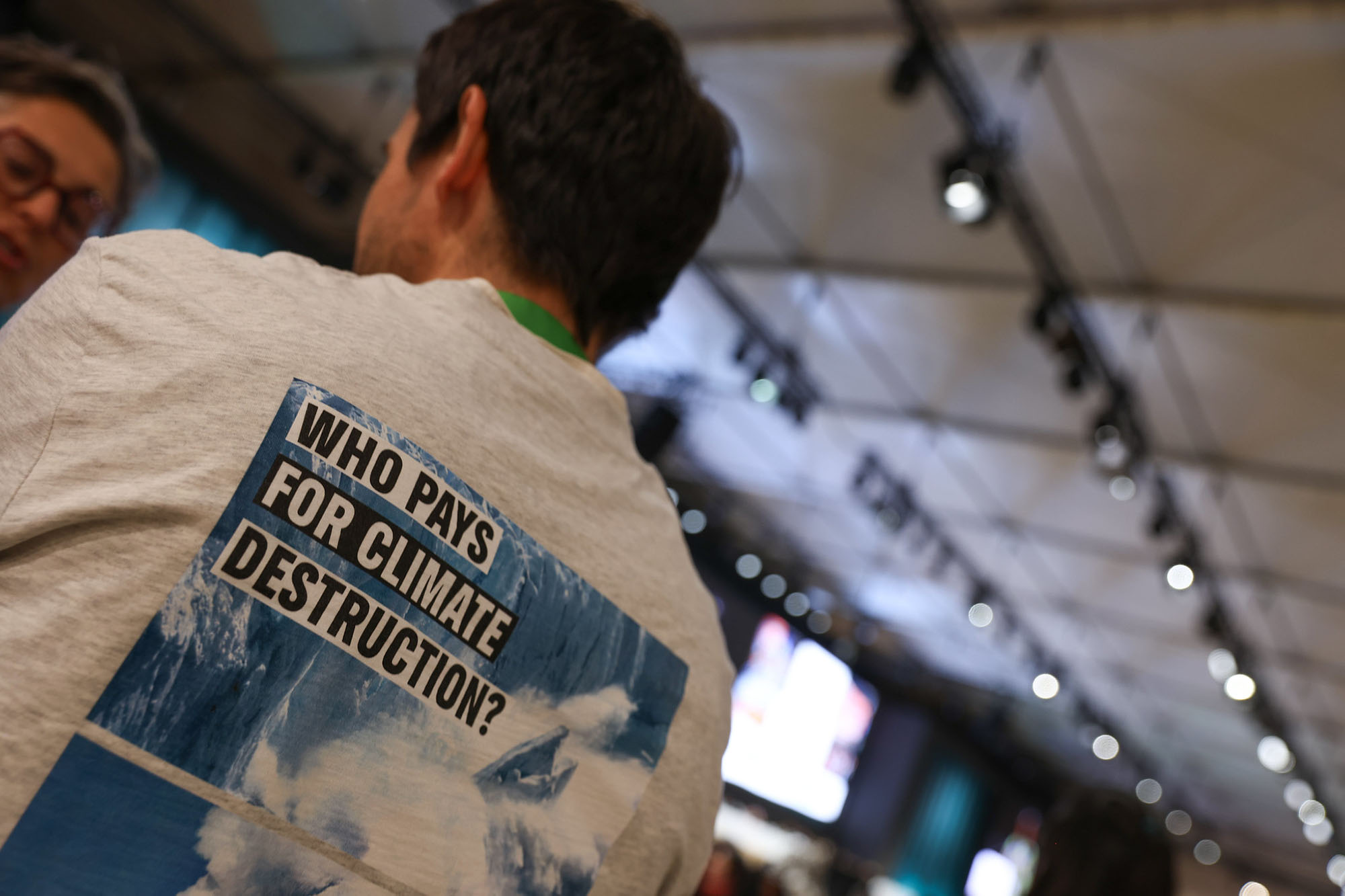 COP29 participant wearing a t-shirt with the message: Who pays for climate destruction?